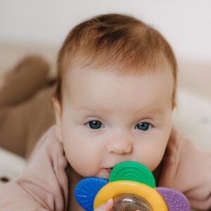 Cute baby playing with a colorful teething toy, perfect for parenting and lifestyle themes.
